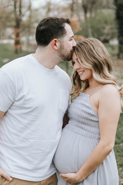 Couple cuddling baby bump during maternity photo session