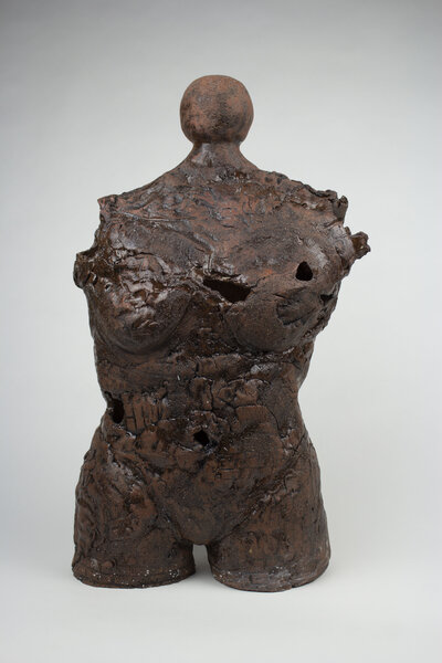 A ceramic bust of a feminine body with various cracks and brick textures