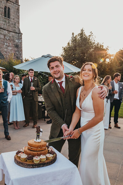 bride and groom laugh whilst cutting cake