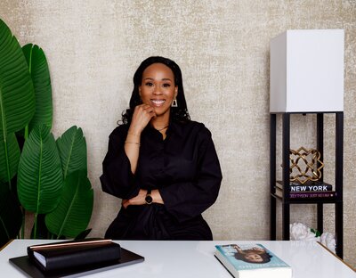 Charmaine Green Forde CEO of Chapter tOO™ sitting at a desk and smiling at the camera