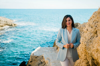 Smiling female CFO finance professional in a blue jacket with the seaside in the background