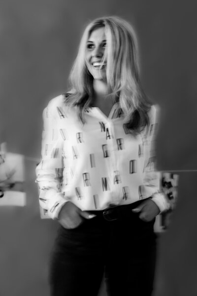 Black and white blurry photo of Sarah Klongerbo in a white shirt with black letters all over it