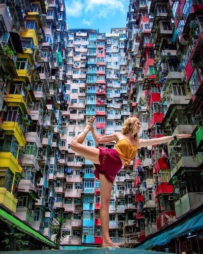 Nomad doing yoga in front of colorful buildings while exploring the city of Hong Kong