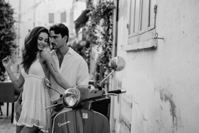 Couple in France posing while leaning on a scooter in France after becoming engaged.