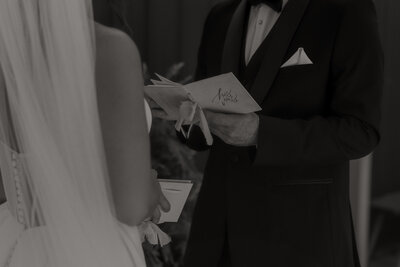 close up of groom holding vow book during first look