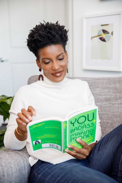 Woman sitting and reading a book with a green cover