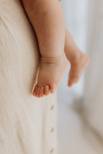 A close up of a babys toes while being held by her mother