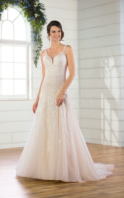 SPARKLY TRADITIONAL A-LINE WEDDING DRESS This sparkly, traditional A-line wedding dress is the perfect amount of glamour for the natural bride! The dropped A-line skirt is totally classic, and the slight V-neckline is subtle yet feminine. The higher back features sheer lace straps and a subtle floating lace detail that frames the V-back. With lace extending from the bodice onto the romantic skirt, the subtle transition of details in this style is completely stunning! With sparkle throughout and a slight train, this gown is also available in plus sizes—highlighting your natural elegance beautifully!