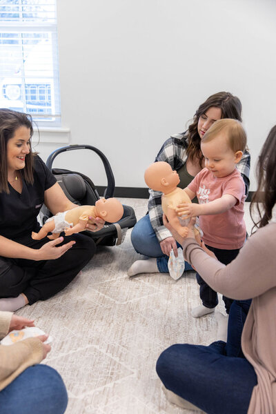 Women practicing placing baby dolls in a car seat 