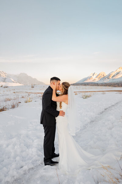 snowy mountain backdrop with bride and groom having an intimate moment kissing. Captured by Michelle Betz Photography