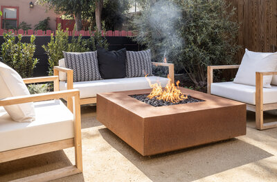 Brass-finish fire table from The Outdoor Plus surrounded by furniture. 