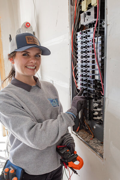 Dove Electric electrician smiling next to electric panel in home