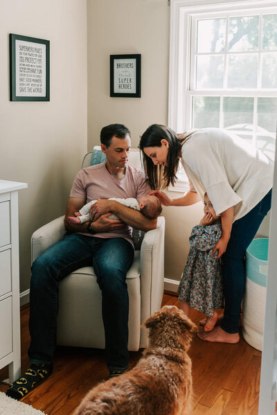 A family looking at the newest family member sleeping in dad's arms