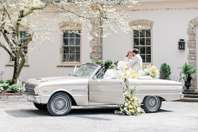 bride and groom kissing while sitting in a vintage car outside of Glen Manor House
