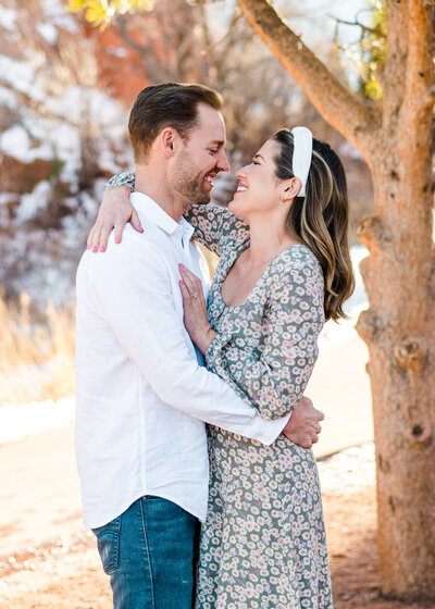 newly engaged couple happily hugging and smiling at each other with a snowy backdrop during engagement session with Colorado Springs Wedding Photographer Erin Winter
