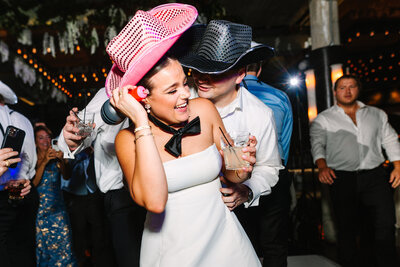 Bride and groom wearing cowboy hats dancing together at reception
