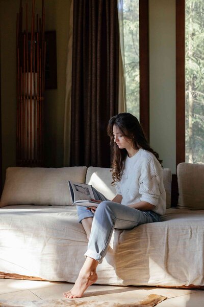 A woman sitting on her couch reading a magazine relaxing between study periods.