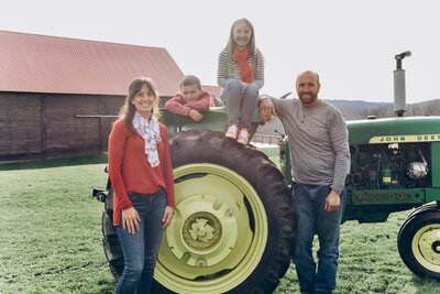 A family of four posing beside a tractor