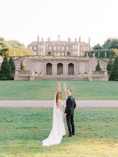 bride in luxurious lace wedding gown posed by window