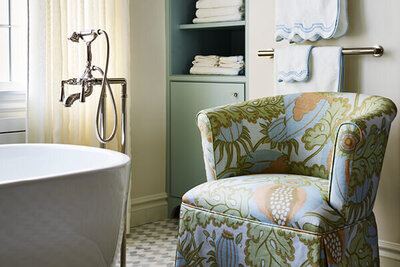 Interior designer in Boston completed a luxury bathroom design with modern fixtures and a custom upholstered slipper chair in Christopher Farr cloth, part of a Milton renovation.