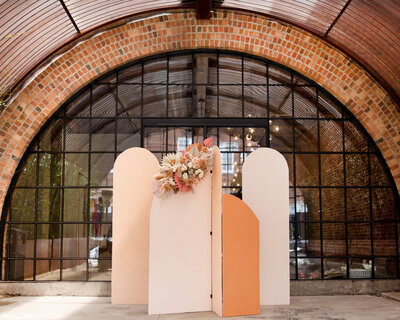 Tan and orange arch backdrop design with florals