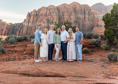 family standing and posing for photos on red rocks at snow canyon state park at the petrified sand dunes