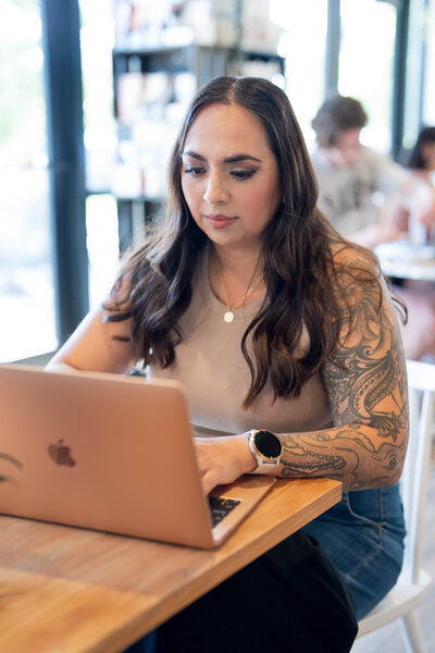 Stephanie, Founder of BCWise Consulting, sitting at a coffee shop on her laptop
