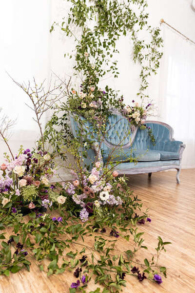 Antique tufted light blue velvet couch with an array of viney purple florals in front