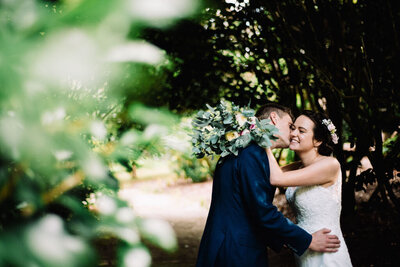 A couple on their wedding day kissing in a woodland area taken by Cornwall Wedding Photographer and Devon Wedding Photographer Liberty Pearl at Scorrier House in Cornwall, UK