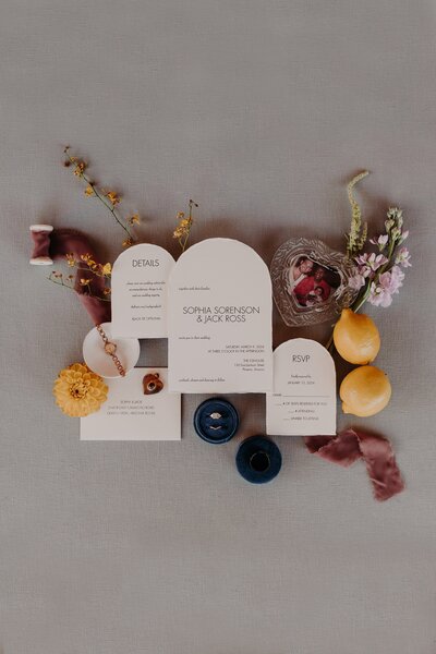 Flatlay of wedding invitation arranged with lemons and florals and family heirlooms