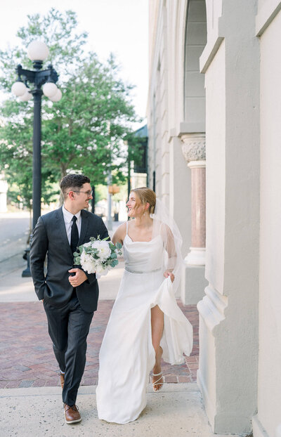 Elegant city wedding as newlyweds walk through historic streets. Timeless urban romance by Jackson Ms Wedding Photographer.