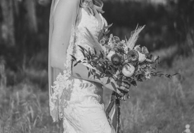 A bride poses with her wedding bouquet by The Teal Door