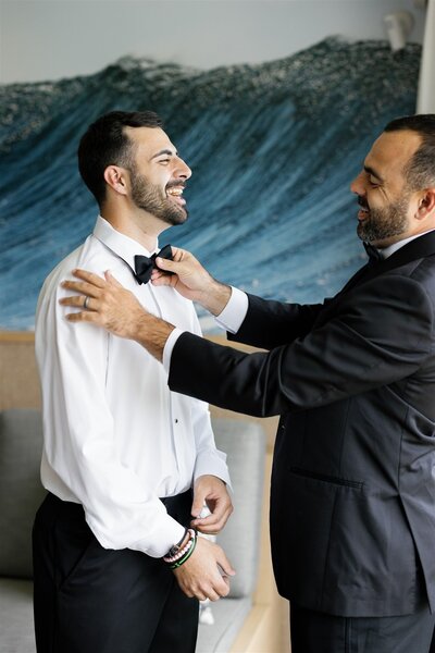 A person helping someone adjust a bowtie 