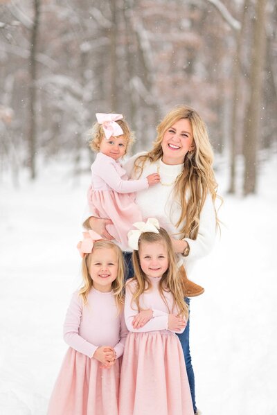 Mom and three young daughters in the snowy woods