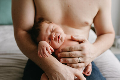 A proud dad and his baby boy sleeping in his his hands. The baby is relaxed and tiny against his dad