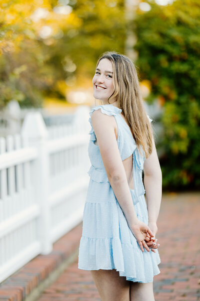 Senior girl in blue dress smiles over shoulder in Portsmouth, New Hampshire