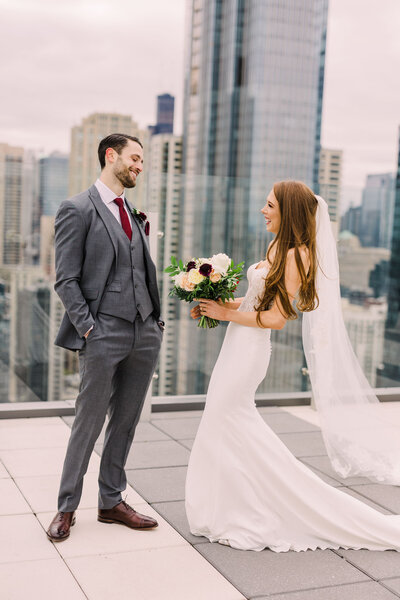 A candid wedding photo of a bride and groom laughing together while taking portraits in the lush gardens of the Art Institute of Chicago.