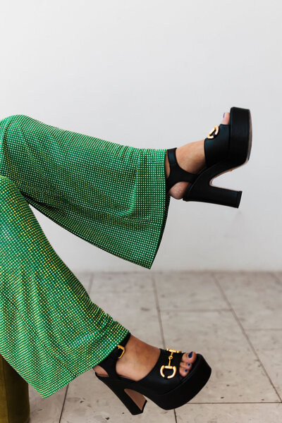 Closeup of legs kicked up on table wearing black heels