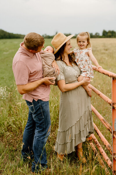 family of four pose in field