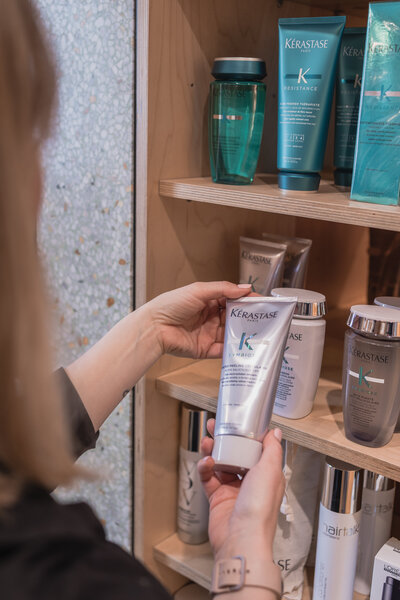photo of woman picking up a bottle of kerastase shampoo