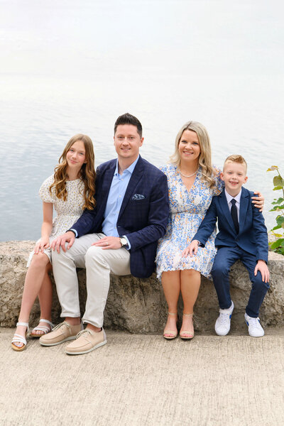 mom and dad with their son and daughter sitting in front of lake Ontario for the family photos.
