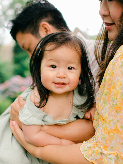 Baby girl smiles for a family photo taken by amsterdam photographer, sim sawyers