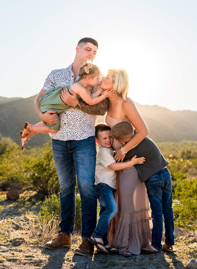 Sweet family of 5 cuddled together, hugging outdoors at sunset in Arizona