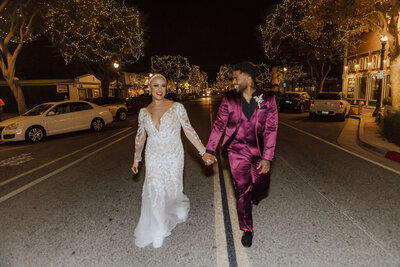 A Bride and Groom walk together, hand in hand, down Main Street. 