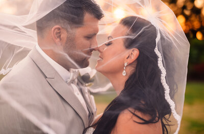 bride and groom looking at each other under bridal veil