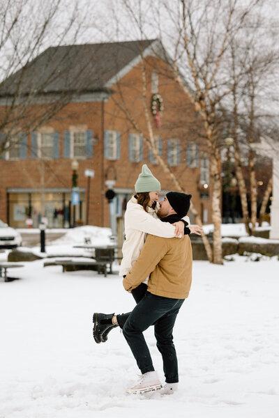 Man holding up woman and spinning in the snow.