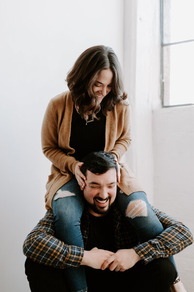 A woman sitting on a man's shoulders laughing