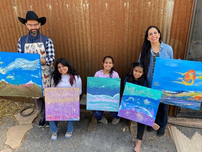 family holding paintings they painted