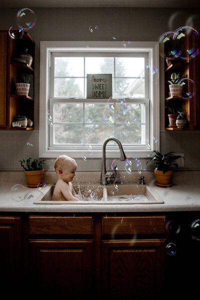 child in sink with bubbles