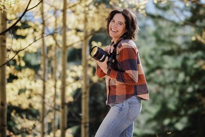 Colorado Elopement Photographer smiles with her camera during fall Colorado wedding.